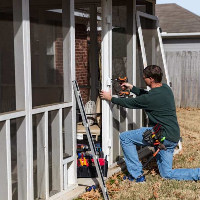 Homeowner works on repairing door to screened in back porch